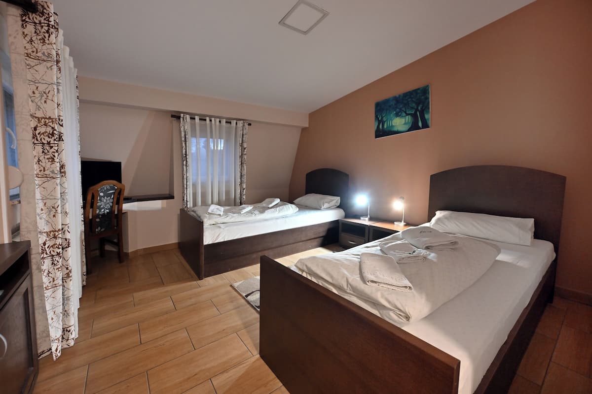 A hotel room with two beds, a desk, a chair, a TV, and a painting on the wall.