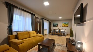A living room with a sofa, coffee table, and a TV mounted on the wall.