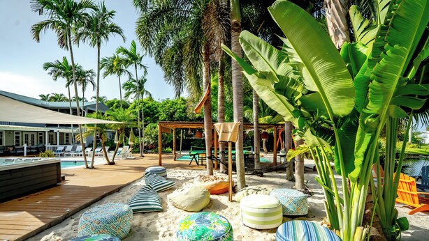 A beachside area with lounge chairs, a wooden deck, and a pool. - Serenity Stays (West Palm Beach)