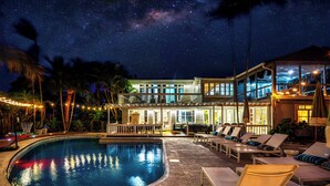 A swimming pool with lounge chairs and a building with multiple floors and balconies. - Serenity Stays (West Palm Beach)