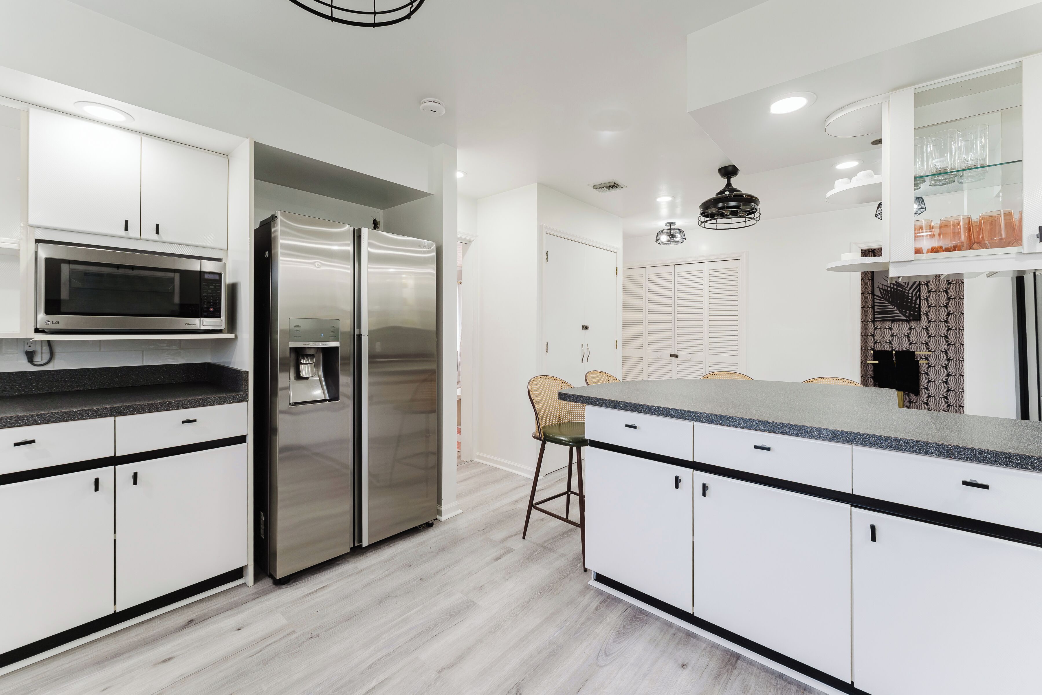 A modern kitchen with white cabinetry, stainless steel appliances, and a central island with seating.