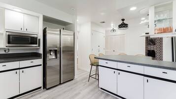 A modern kitchen with white cabinetry, stainless steel appliances, and a central island with seating.