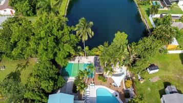 An aerial view of a residential area with a large pond, surrounded by lush greenery and houses.