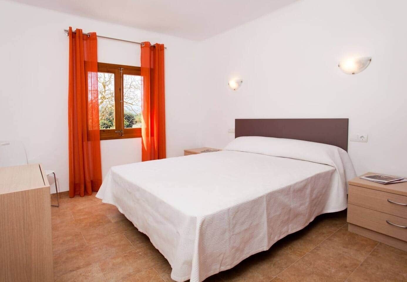 Une chambre à coucher avec un lit, un bureau et une fenêtre avec des rideaux.