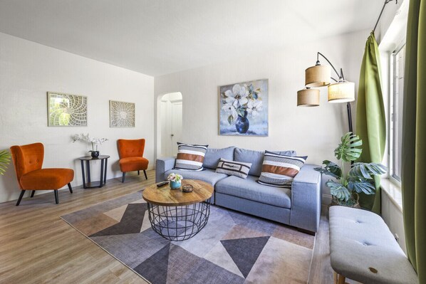 A living room with a sofa, two armchairs, a coffee table, and a painting on the wall.