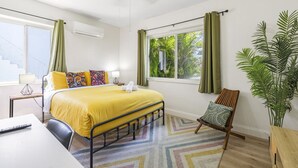 A hotel room with a bed, a desk, a chair, a plant, and a window with curtains. - Urban Oasis • Modern Comfort in Prime Location (Miami)
