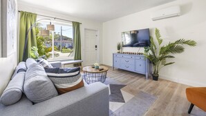 A living room with a sofa, a coffee table, a TV, a blue cabinet, and a large plant. - Urban Oasis • Modern Comfort in Prime Location (Miami)