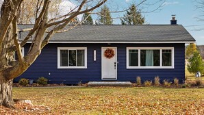 A single-story house with a dark blue exterior, white trim, and a front door with a wreath.