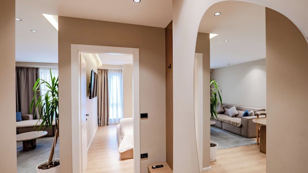 Un interior moderno con un pasillo que conduce a una sala de estar, un sofá y una mesa de comedor.