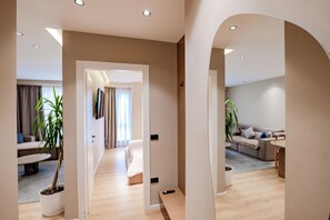 A modern interior with a hallway leading to a living area, a sofa, and a dining table. - Agate Hotel Tirana (Tirana)