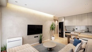 Una sala de estar moderna con un televisor de pantalla plana, una mesa de centro redonda y un sofá.