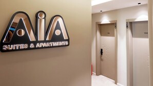 Un pasillo con un cartel que indica 'AIA Suites & Apartments' y dos puertas con las etiquetas '103' y '102'.