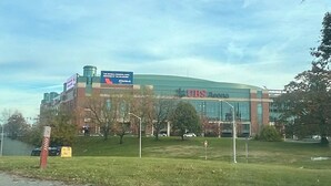Un edificio grande con un llamativo letrero que dice 'UBS Arena', rodeado de césped y árboles.
