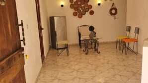 Un comedor con mesa y sillas, un refrigerador y adornos en la pared.