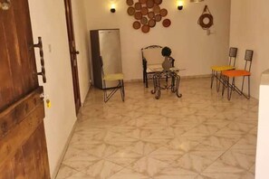Un comedor con mesa y sillas, un refrigerador y adornos en la pared.