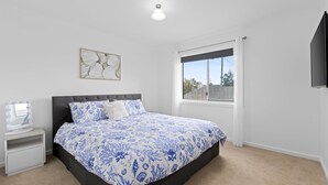 Une chambre à coucher avec un lit, une coiffeuse avec un miroir et une fenêtre donnant sur l’extérieur.
