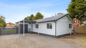 Une maison de plain-pied avec un porche abrité, un garage et une cour arrière clôturée.