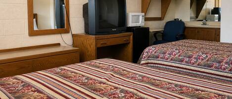 Habitación de hotel con dos camas, televisión, microondas, escritorio y una silla.