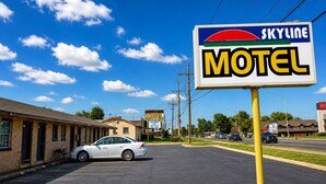 A motel with a parking lot, a white car parked in front, and a clear blue sky.