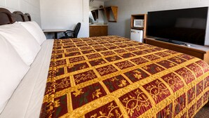 A hotel room with a large bed, a TV, a desk, and a chair.