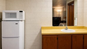 A compact kitchenette with a microwave, refrigerator, and sink.