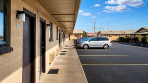 A motel with a covered walkway, multiple rooms, and a parking lot.