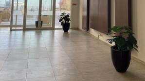 A spacious lobby with large windows, a modern ceiling design, and potted plants. - Apartment in secure residence with swimming pool, waterfront location (Sousse)