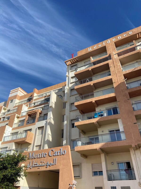 Un immeuble résidentiel à plusieurs étages, doté de balcons et d’une enseigne indiquant « Monte Carlo ».