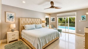 A bedroom with a large bed, a ceiling fan, and a view of a swimming pool through glass doors. - Private Pool • 10 Min to Siesta Key Beach • Stylish Sarasota Retreat (Sarasota)