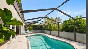 A swimming pool with a clear blue water, surrounded by a covered patio area with lounge chairs. - Private Pool • 10 Min to Siesta Key Beach • Stylish Sarasota Retreat (Sarasota)