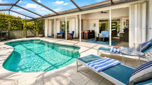 A swimming pool with lounge chairs and a covered patio area. - Private Pool • 10 Min to Siesta Key Beach • Stylish Sarasota Retreat (Sarasota)