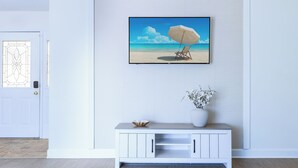 A room with a white door, a white console table with a bowl and vase, and a framed picture of a beach scene. - Family home with private heated pool and patio, near Anna Maria Island & IMG. (Bradenton)