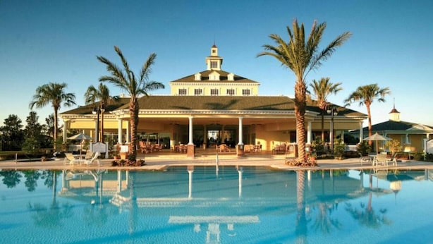 Ein Hotel mit Pool, Palmen und einer überdachten Terrasse.