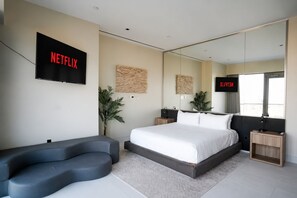 A modern bedroom with a large bed, a TV mounted on the wall, and a mirror reflecting the room. - A+ Location • Hot Tub & Strip Views • Gym & Pool (Las Vegas)
