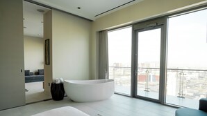 Une chambre d’hôtel moderne dotée d’un grand lit, d’une baignoire et d’un balcon offrant une vue sur la ville.