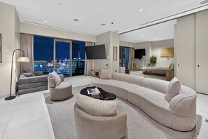 A modern living room with a large sectional sofa, a coffee table, and a flat-screen TV.
