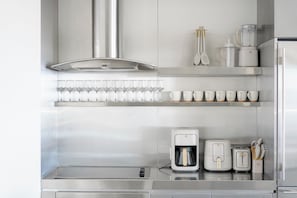 A modern kitchen with stainless steel appliances, a coffee maker, a toaster, and a set of cups and glasses on shelves. - A+ Location • Hot Tub & Strip Views • Gym & Pool (Las Vegas)