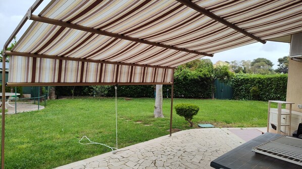 A covered patio area with a grill and seating.