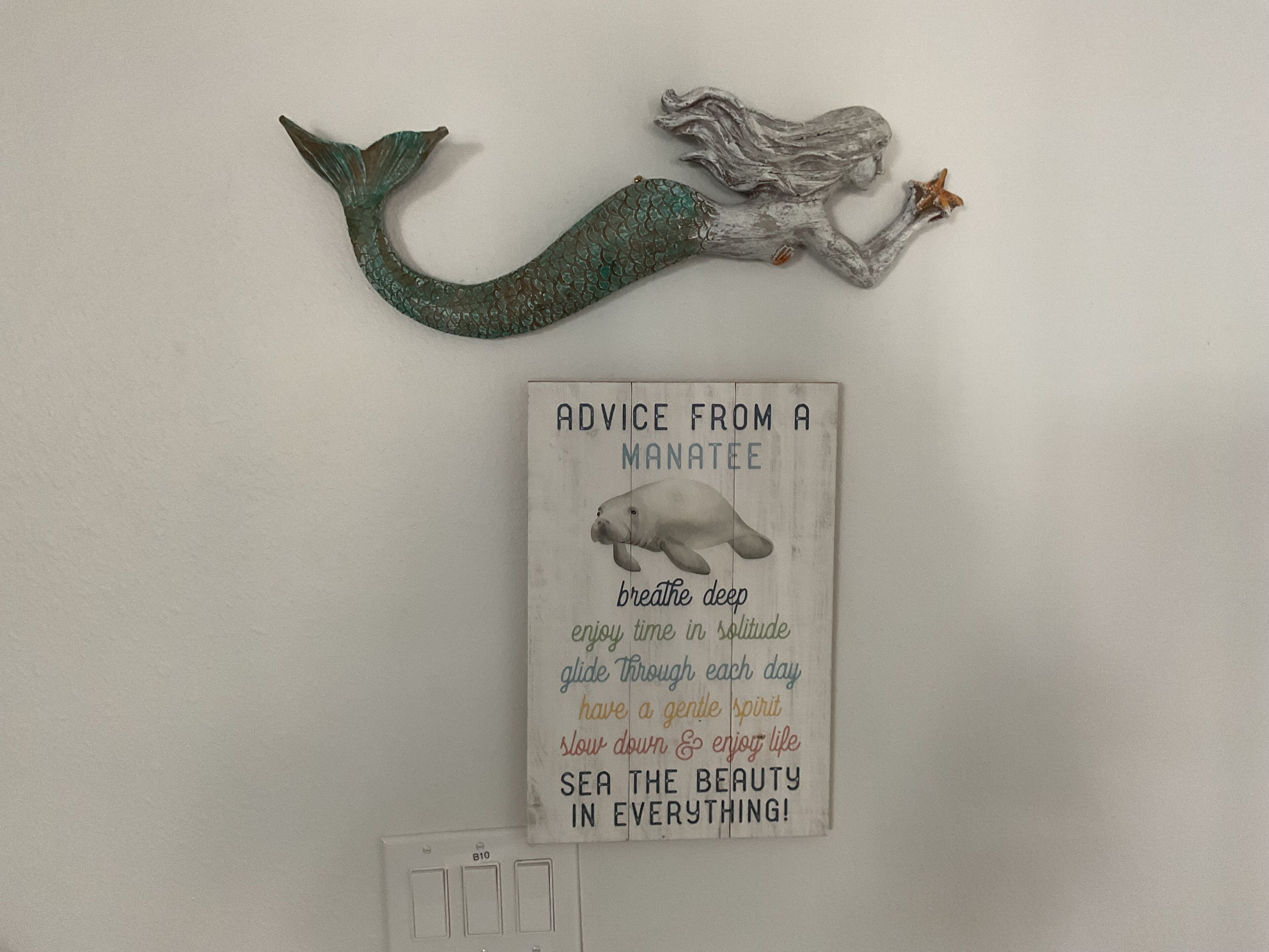 Un mur orné d’une statuette de sirène et d’une pancarte affichant des conseils donnés par un lamantin.