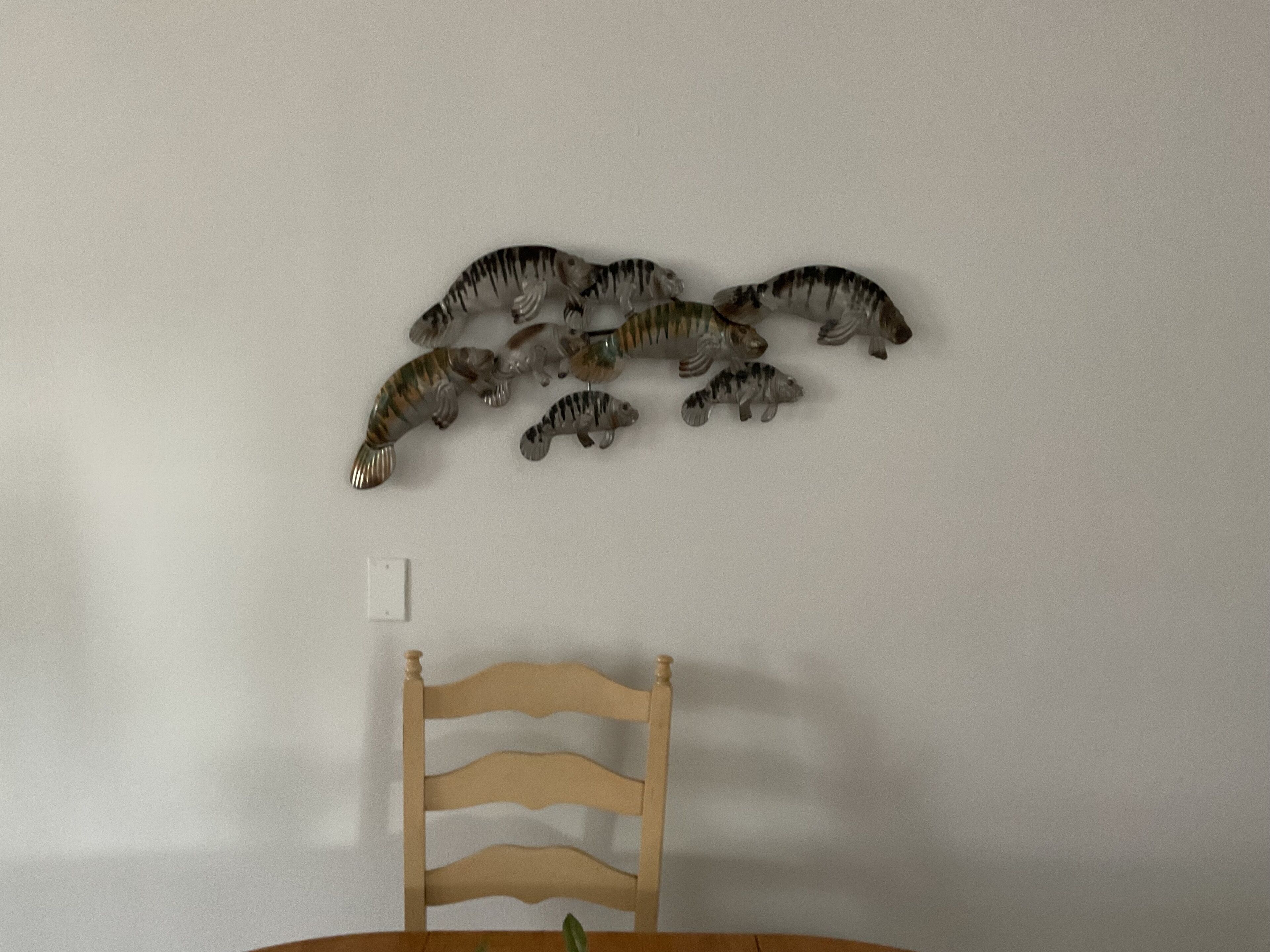 Een muur met een rij dinosaurusbeeldjes en een houten stoel eronder.