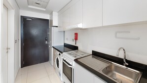 A compact kitchen with a washing machine, a stove, and a sink.