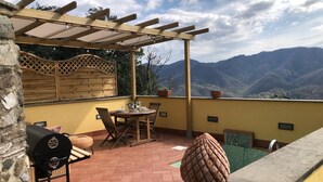 A patio with a wooden pergola, a grill, and a view of mountains. - Cà La Torre, Stone House with pool in the terrace and super view (Bibola)