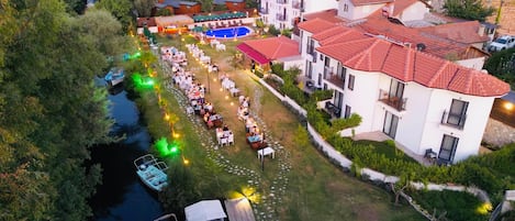 An aerial view of a residential area with a swimming pool, boats, and houses with red-tiled roofs.