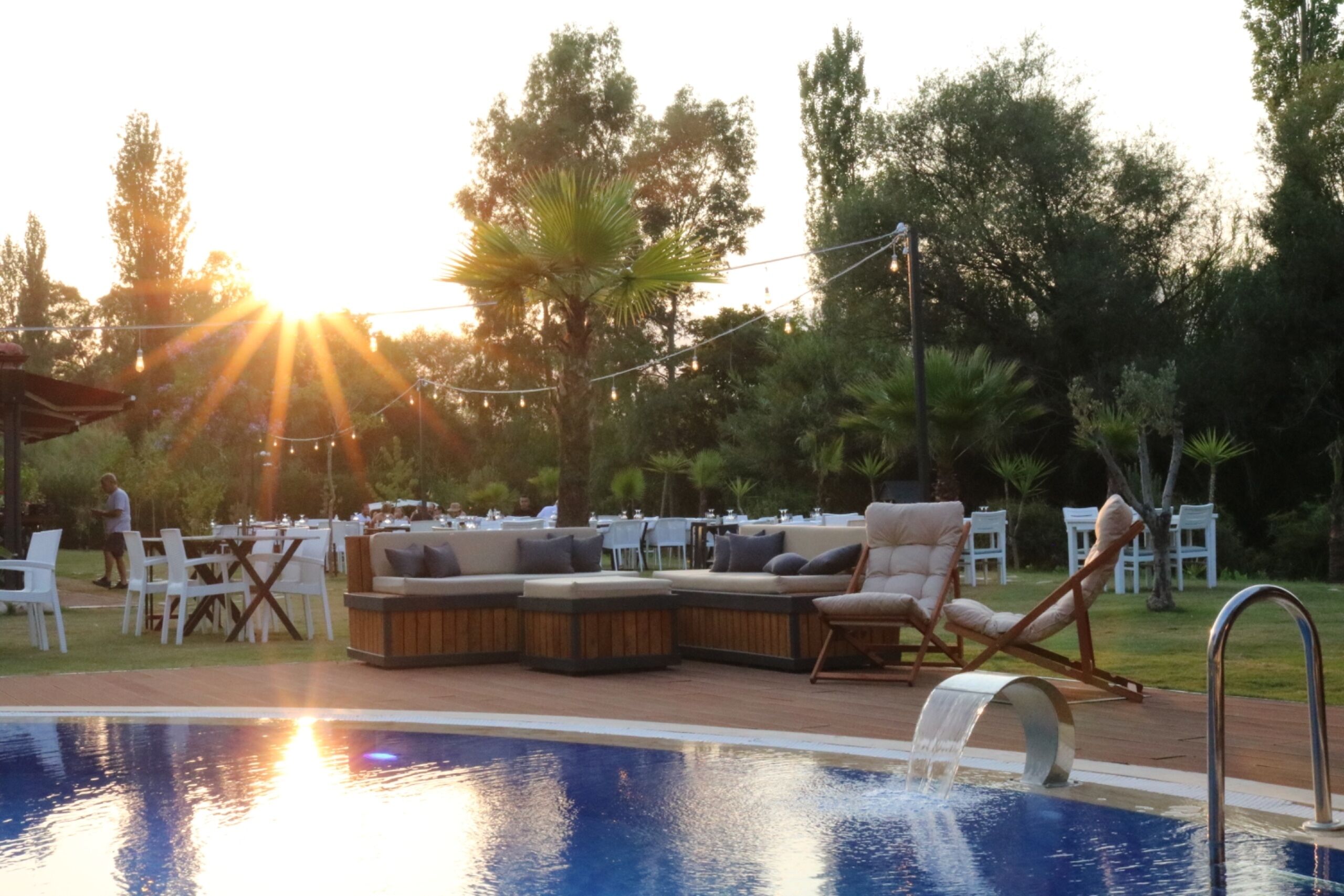 Un espace aménagé au bord de la piscine, avec des sièges, une piscine et des guirlandes lumineuses.