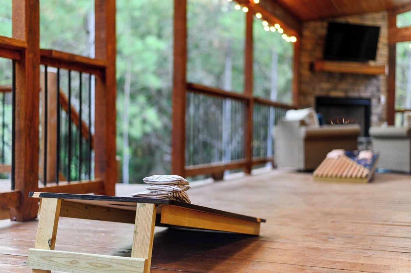 A wooden deck with a small table and chairs, a fireplace, and a TV mounted on the wall.