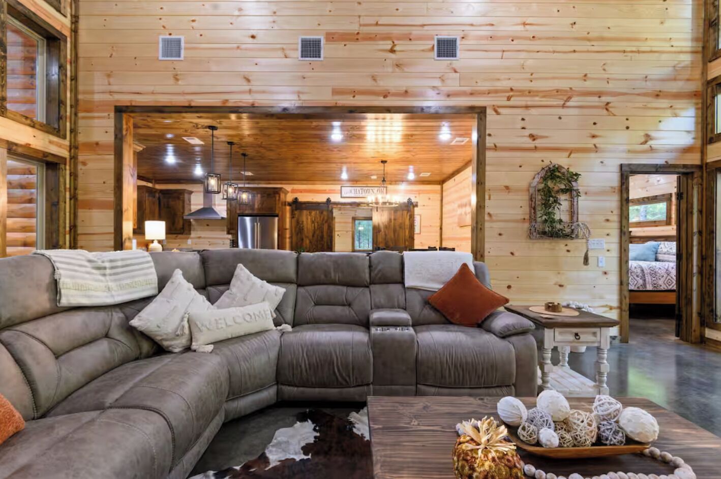 A cozy log cabin interior with a sectional sofa, a wooden coffee table, and a rustic decor.