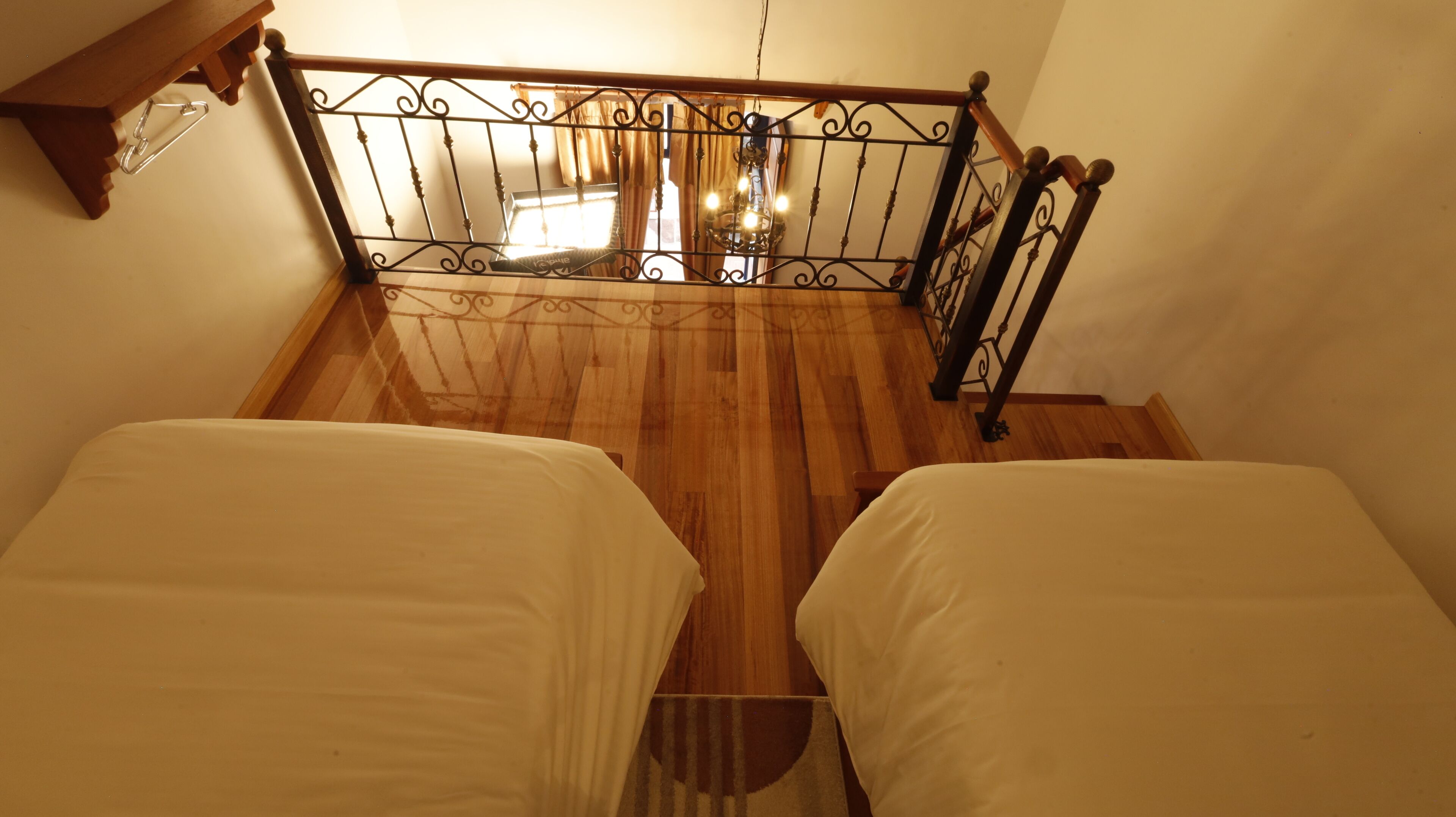 Uma escadaria com corrimão de ferro que leva a um quarto com duas camas.