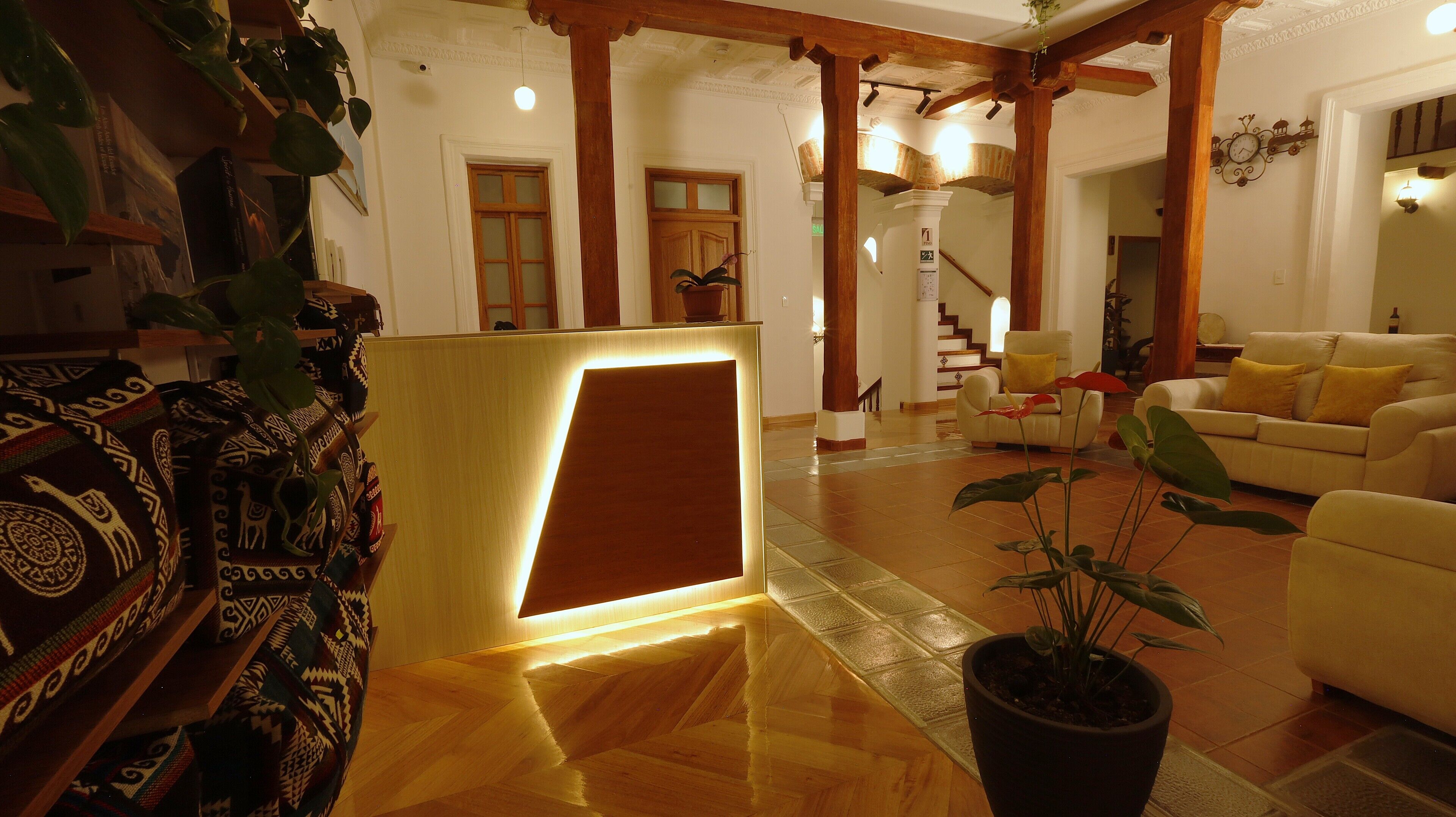 A spacious lobby with a reception desk, a staircase, and a seating area with a sofa and armchairs.