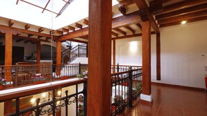 Un interior espacioso con vigas de madera y un balcón con plantas en macetas.
