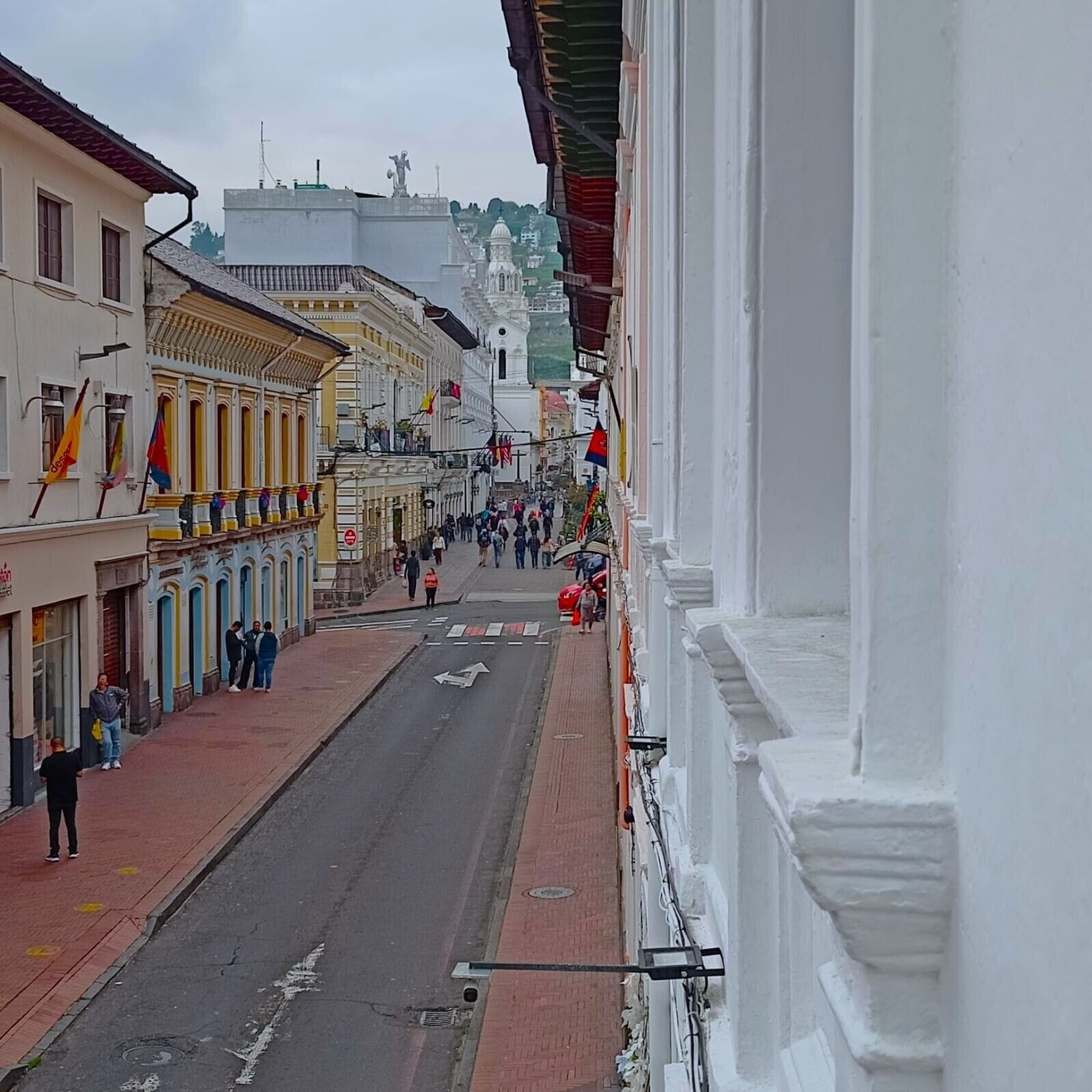 Vista de una calle con edificios, una carretera despejada y peatones.